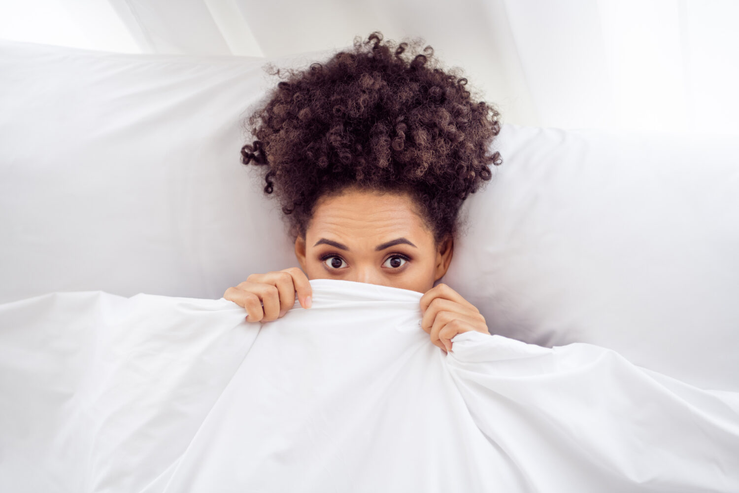 Woman hiding under a warm blanket