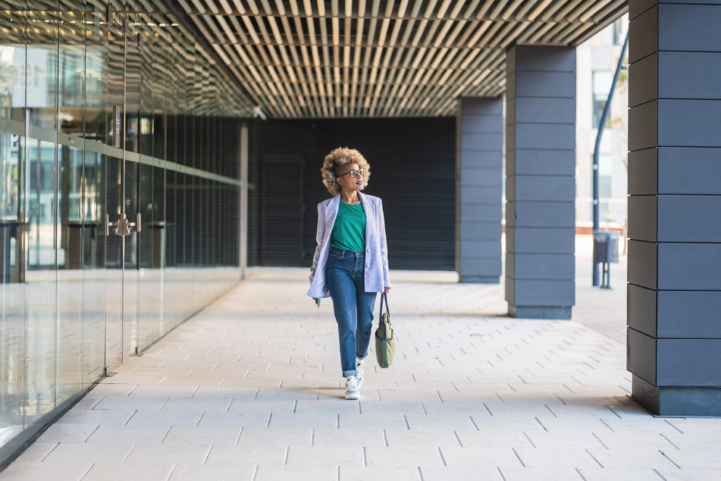 Woman walking through a modern city corridor, reflecting the pressures of mental load and expectations placed on women.