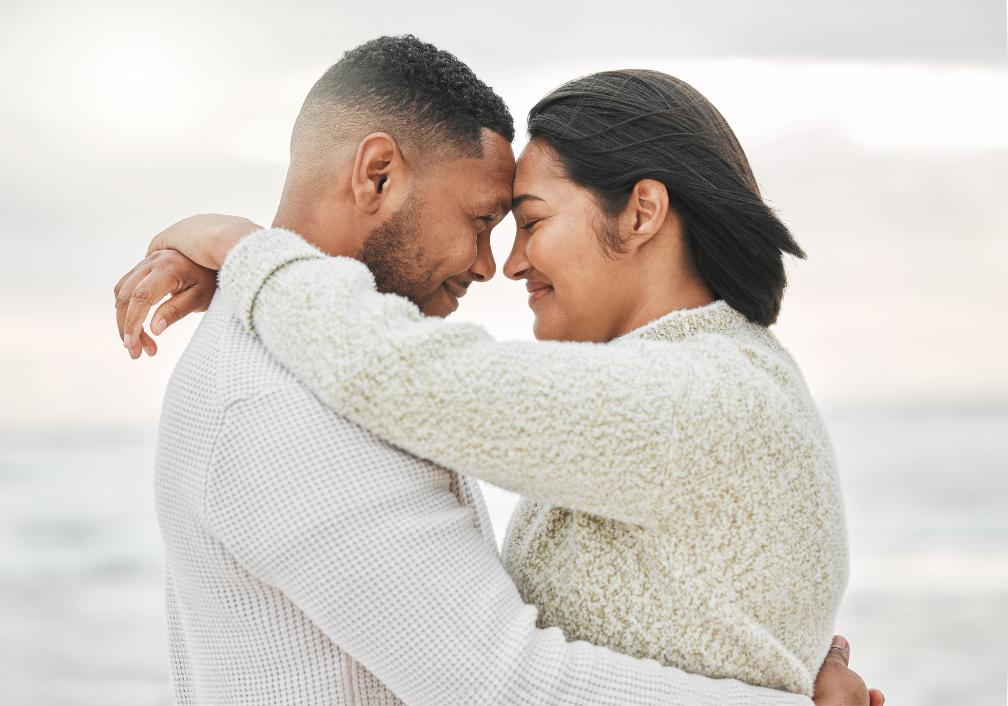Happy couple touching foreheads on the beach