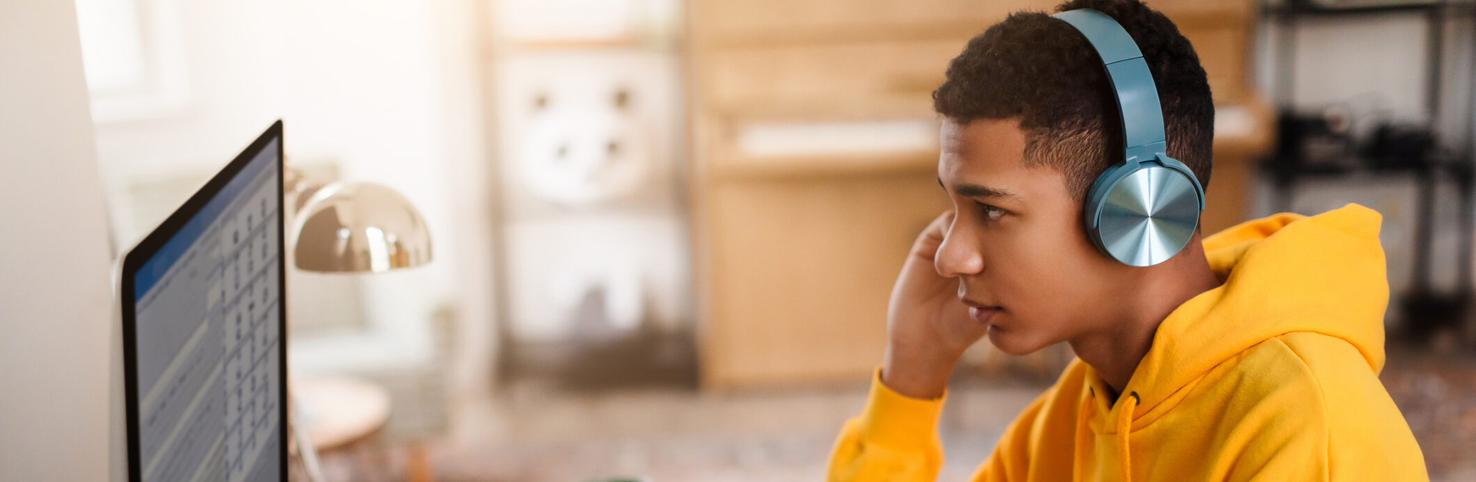 Male teen taking an assessment with headphones on sitting at a computer
